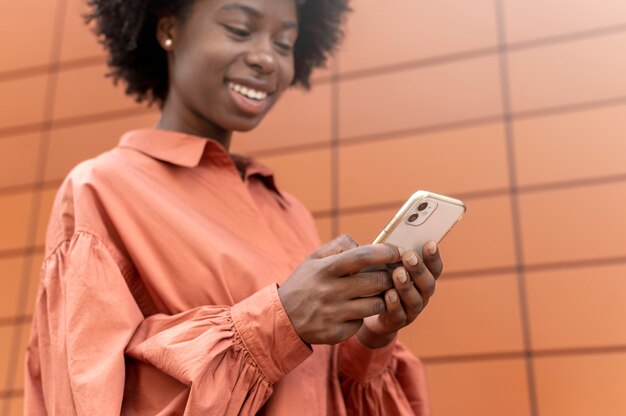 Mulher afro-americana enviando mensagens de texto para alguém em seu smartphone