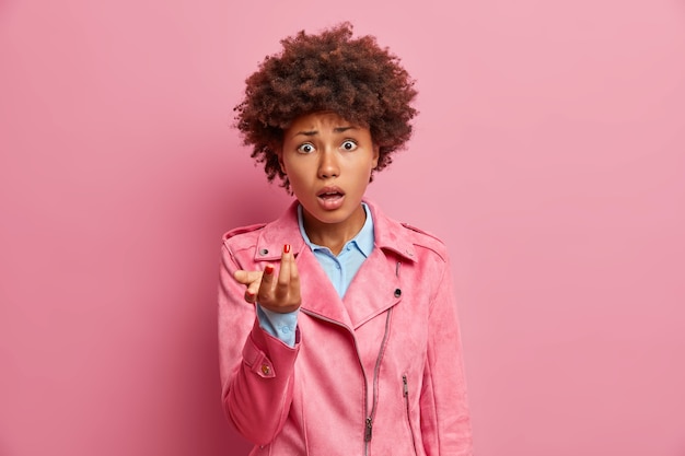 Mulher afro-americana intrigada e frustrada levanta a palma da mão e parece indignada