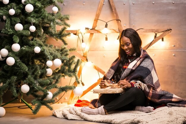 Mulher afro-americana que desembala presentes de Natal