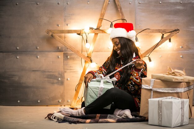 Mulher afro-americana que desembala presentes de Natal