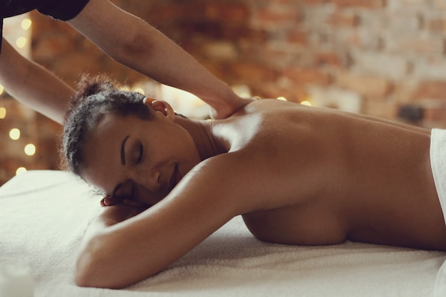 Mulher afro-americana, recebendo uma massagem relaxante no spa