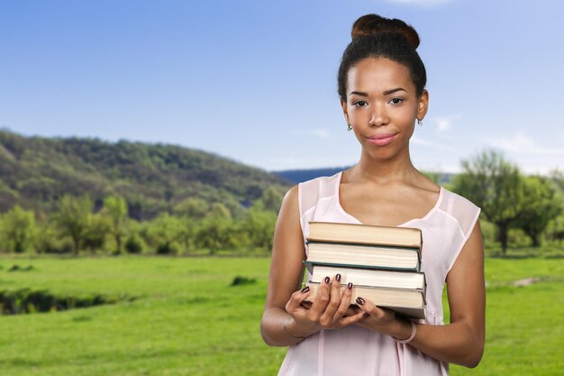 Mulher afro-americana segurando uma pilha de livros