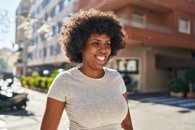 Mulher afro-americana sorrindo confiante olhando para o lado na rua
