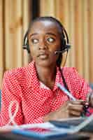 Foto grátis mulher afro-americana trabalha em um operador de call center e agente de atendimento ao cliente usando fones de ouvido de microfone trabalhando no laptop