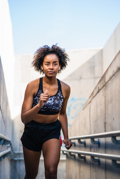 Mulher afro-atlética correndo e fazendo exercícios ao ar livre