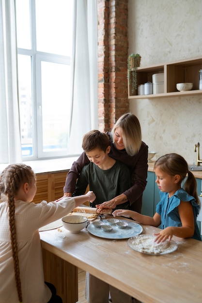 Foto grátis mulher ajudando crianças a cozinhar tiro médio