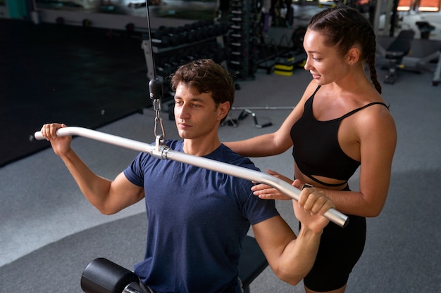 Mulher ajudando homem a treinar alto ângulo