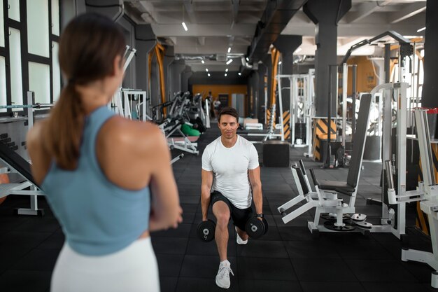 Mulher ajudando homem na academia