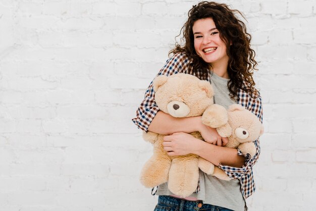 Foto grátis mulher alegre abraçando brinquedos de pelúcia