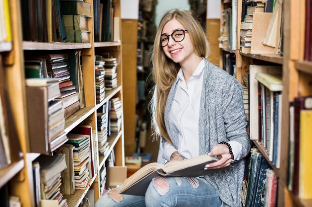 Mulher alegre com livro na biblioteca