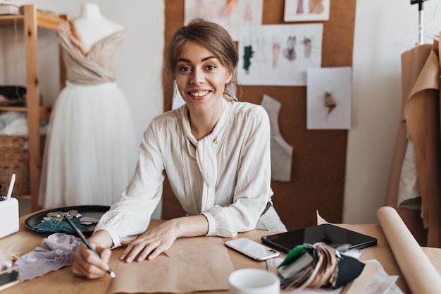 Mulher alegre em uma blusa elegante desenhando um esboço