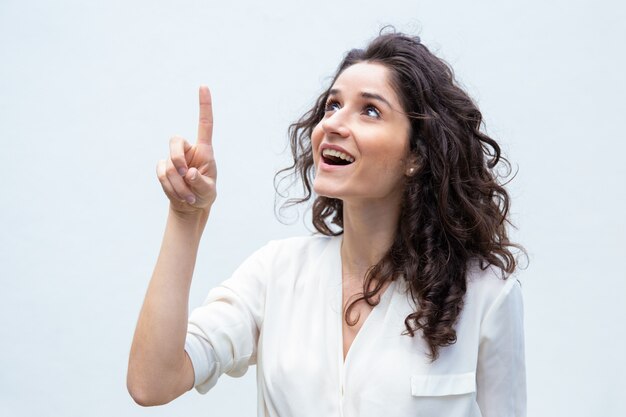 Mulher alegre feliz, apontando o dedo para cima