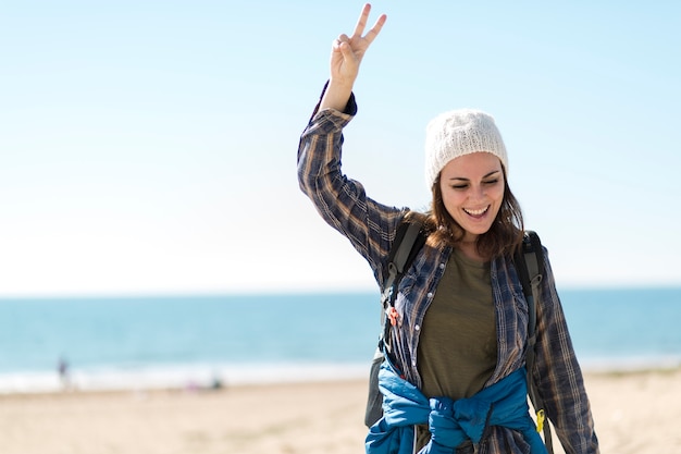 Mulher alegre, gesticulando paz na praia