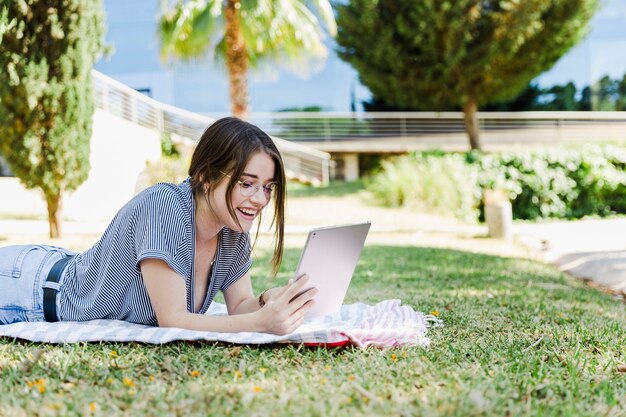 Mulher alegre navegando tablet no parque