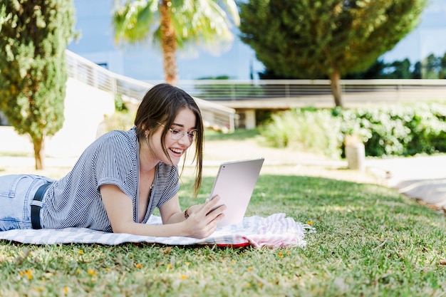 Mulher alegre navegando tablet no parque