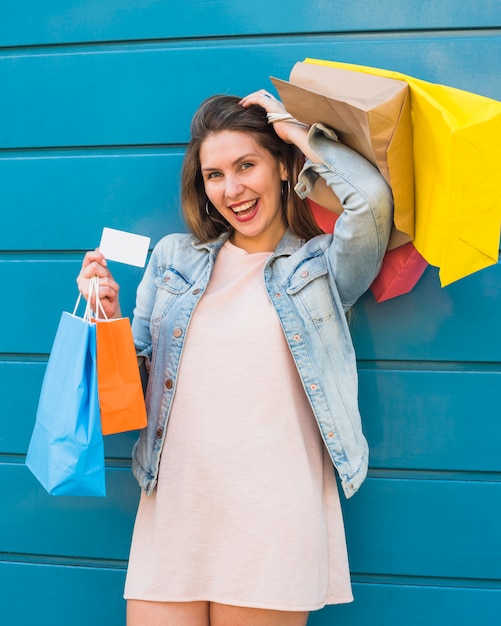 Mulher alegre permanente com sacos de compras e cartão de crédito
