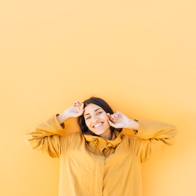 Mulher alegre posando contra o pano de fundo amarelo liso