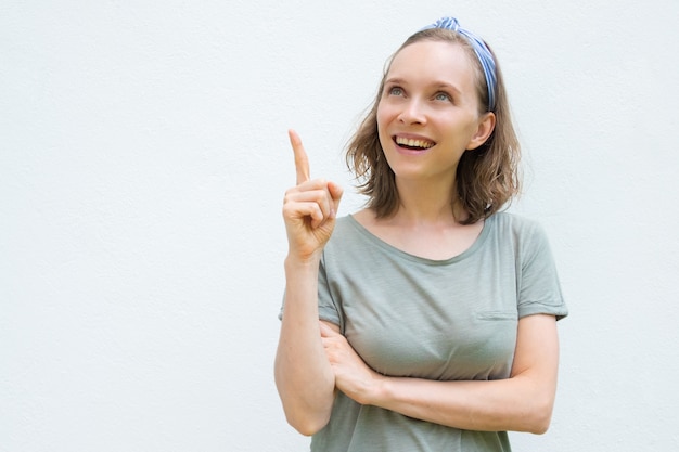 Mulher alegre positiva em roupas de verão, apontando para cima