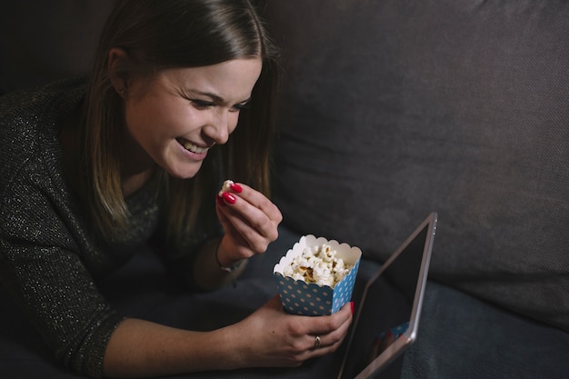 Mulher alegre que assiste o filme no comprimido