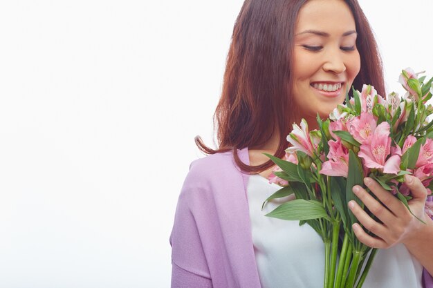 Mulher alegre que cheira suas flores