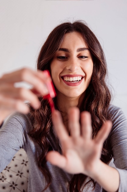 Mulher alegre que pinta as unhas