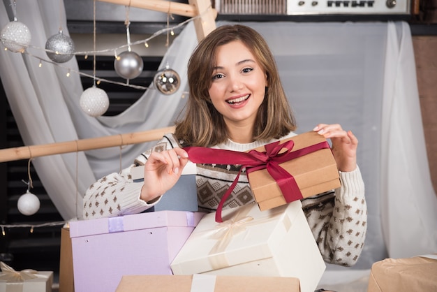 Mulher alegre segurando um presente de natal na sala de estar.