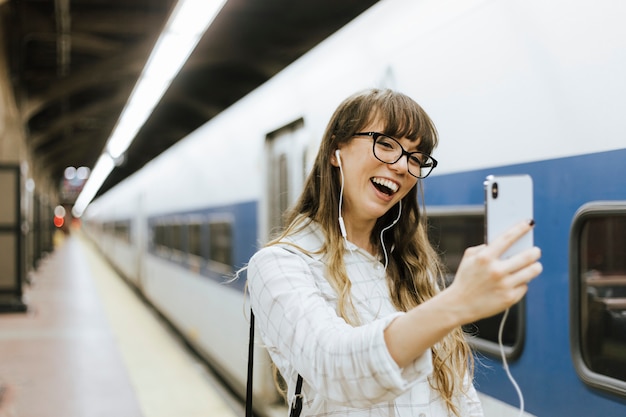 Mulher alegre, tendo uma chamada de vídeo em uma plataforma de metrô