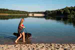 Foto grátis mulher andando com cachorro na praia tiro completo