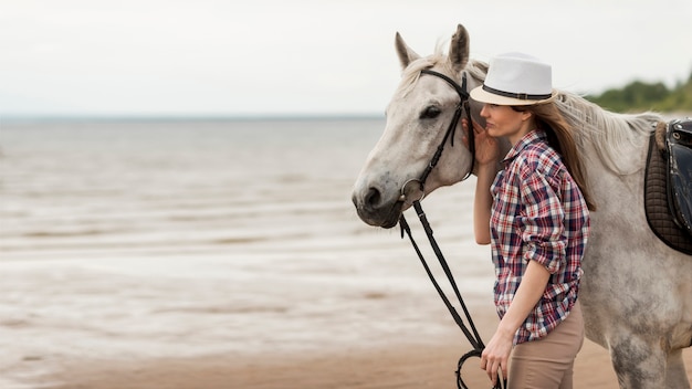 Mulher andando com um cavalo na praia