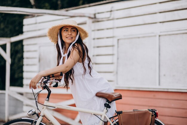 Mulher andando de bicicleta com vestido e chapéu