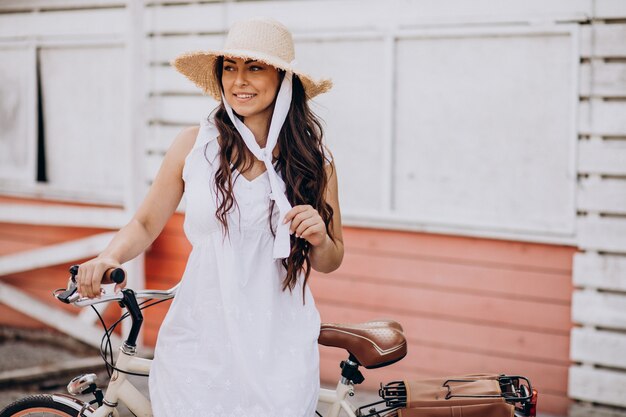 Mulher andando de bicicleta com vestido e chapéu