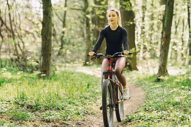 Mulher andando de bicicleta de montanha na floresta