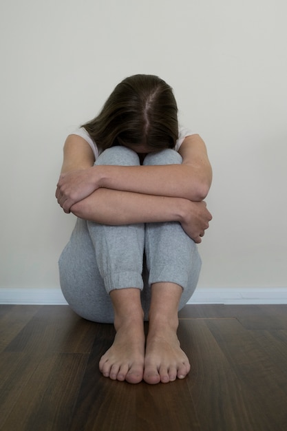 Mulher ansiosa de tiro completo sentada no chão