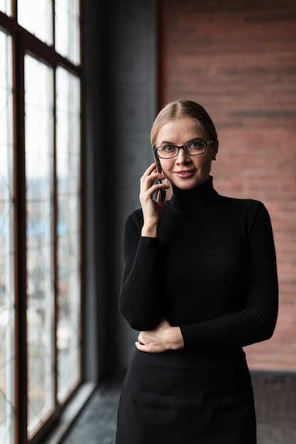 Mulher ao lado da janela, falando por telefone