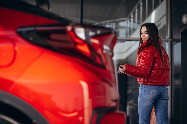 Mulher ao lado de seu novo carro vermelho