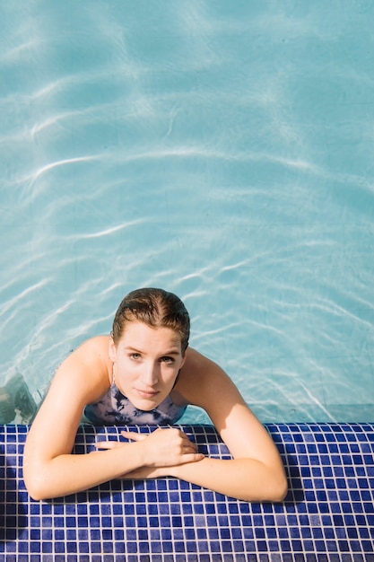 Foto grátis mulher apoiada na beira da piscina
