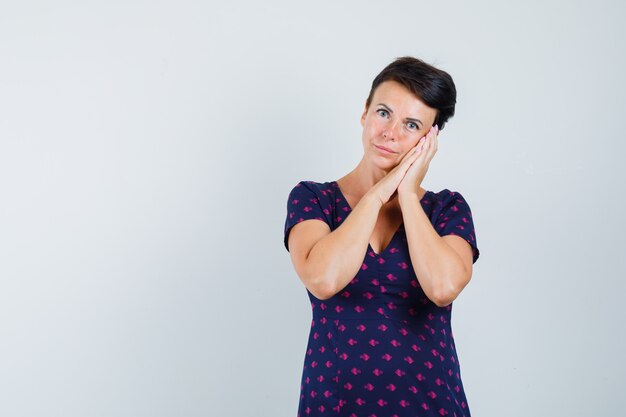 Mulher apoiada nas palmas das mãos como travesseiro no vestido e parecendo calma.