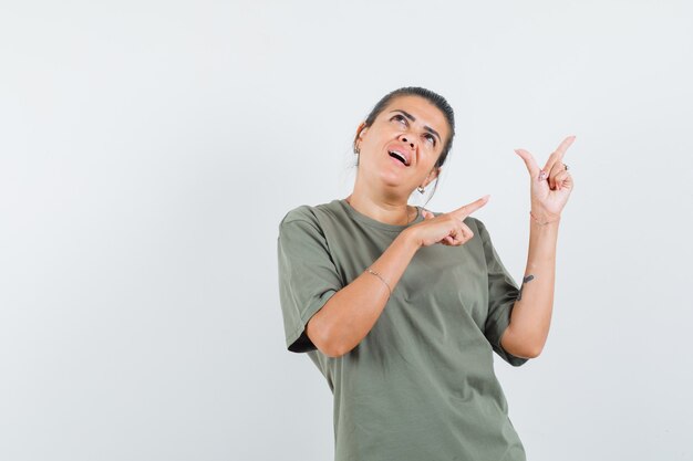 mulher apontando para cima em camiseta e parecendo sonhadora