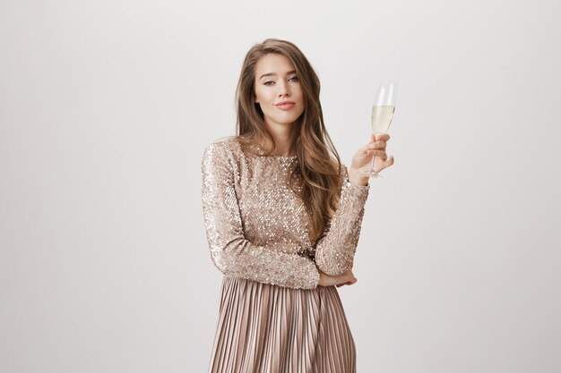 Mulher arrogante em vestido de noite, bebendo champanhe