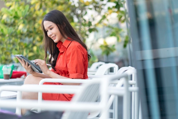 Foto grátis mulher asiática atraente inteligente, pano casual, trabalho freelance, lazer, relaxe trabalhando com tablet e smartphone no café, restaurante, estilo de vida urbano, nômade digital, trabalhando no espaço de trabalho conjunto