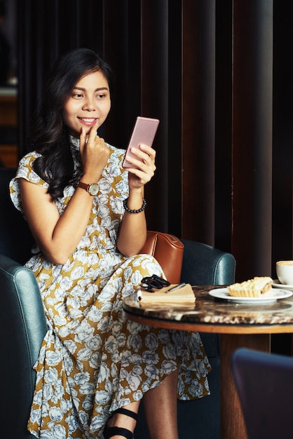 Mulher asiática bonita sentada no café e tomando selfie com smartphone