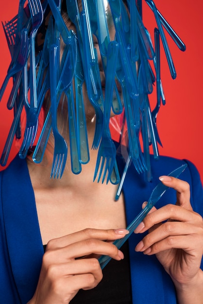 Mulher asiática coberta de talheres de plástico azul