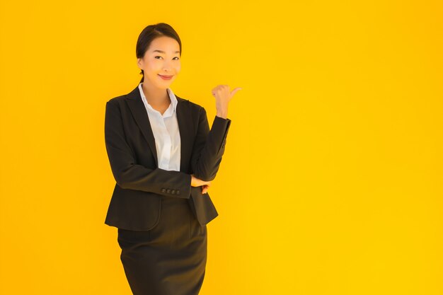 Mulher asiática de negócios jovem bonita com sorriso feliz, apontando para o lado