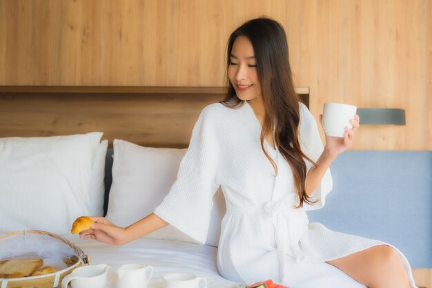 mulher asiática, desfrutando com café da manhã na cama