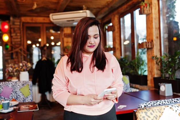 Mulher asiática elegante em roupas casuais posando café interior com telefone à mão