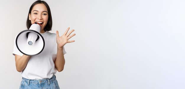 Mulher asiática feliz gritando no megafone fazendo anúncio anunciando algo sobre o whit