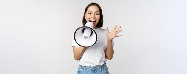 Mulher asiática feliz gritando no megafone fazendo anúncio anunciando algo sobre o whit