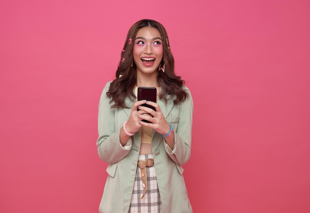 Foto grátis mulher asiática feliz usando telefone celular isolado em fundo rosa