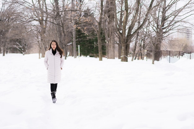 Mulher asiática nova bonita que sorri feliz para o curso na estação do inverno da neve