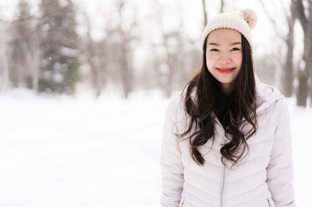 Mulher asiática nova bonita que sorri feliz para o curso na estação do inverno da neve